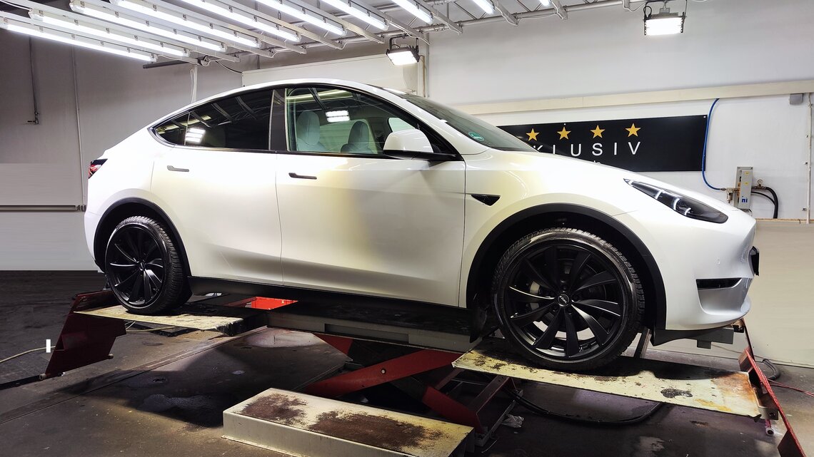 Tesla Model Y auf Hebebühne bei technischer Beleuchtung - der Lack sieht dank Goldshield Keramikversiegelung top aus!