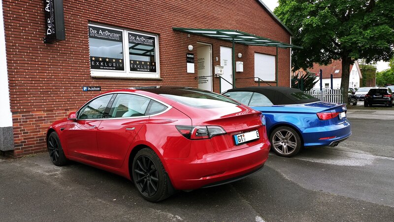 Kostenlose Erstprüfung vor der Werkstatt Zwei Leasingautos nebeneinander - Tesla und Audi